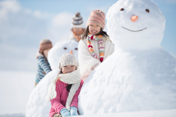 雪だるまの周りで微笑む小学生