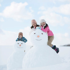 雪だるまと雪遊びをする小学生