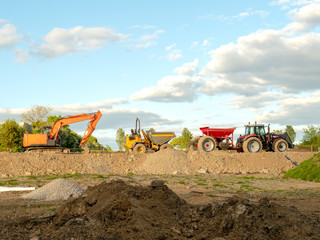 Excavator, dumper, tractor on a construction site, warm, sunny day, blue cloudy sky.
