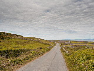 Small country road, Inishmore, Aran islands, Ireland. Fields and dry stone walls, Connemara mountains in background.