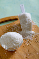 Sugar in glass bowl on wooden background