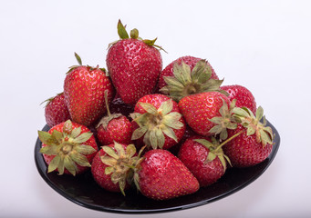 fresh ripe strawberries on black plate isolated on white background