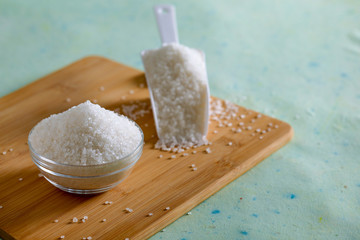 Sugar in glass bowl on wooden background