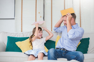 Portrait of caucasian father holding book playing teaching daughter little girl . Home school learn...