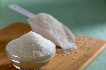 Sugar in glass bowl on wooden background