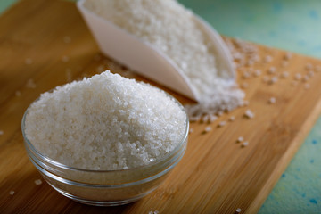 Sugar in glass bowl on wooden background
