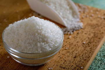 Sugar in glass bowl on wooden background