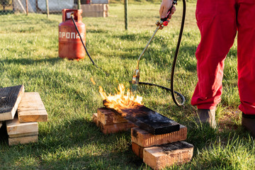 A man burns wooden planks with propane using old-time Japanese technology, creating facing material...