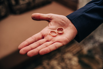 gold wedding rings on the palm of the groom on the wedding day