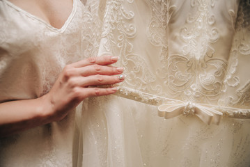 young bride holds her wedding dress with fingers