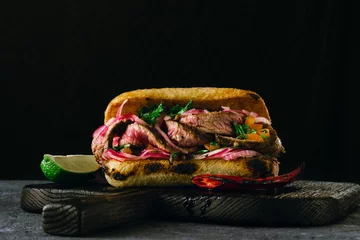 Selbstklebende Fototapeten Steakhouse Grilled spicy steak sandwiches on wooden cutting boards on dark background  © kucherav