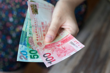 A hand giving Hong kong dollars (HKD) in cash
