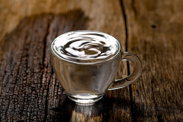 water in cup on wooden background 