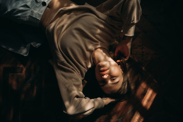 Young woman lies on the floor lit by sun.