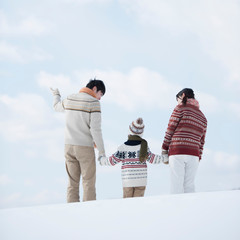 雪原で手をつなぐ家族の後姿