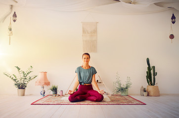 mindfulness, spirituality and healthy lifestyle concept - woman meditating in lotus pose at yoga...