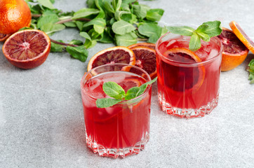 Closeup of cold blood orange margarita cocktail with mint on the grey table