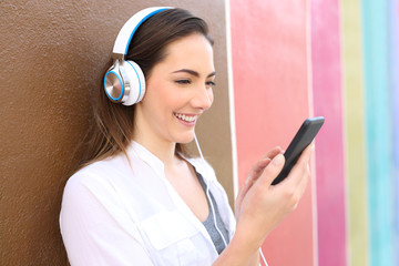 Happy girl listens to music using phone and headphones