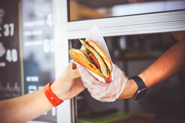 street sale and people concept - happy seller giving burger to customer at food truck