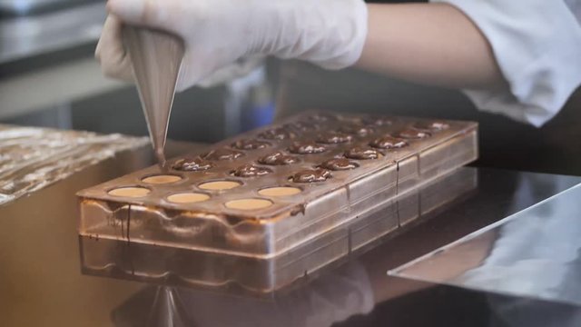 Pastry chef processing chocolate in kitchen.