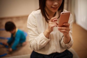 Fototapeta premium スマートフォンの操作に夢中になる母親