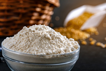 Composition with wheat grains, flour with heart shape on black background