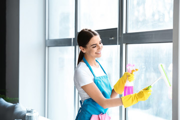 Female janitor cleaning window in office