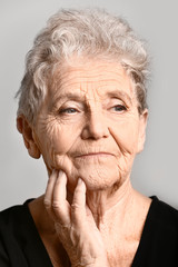 Portrait of senior woman on grey background