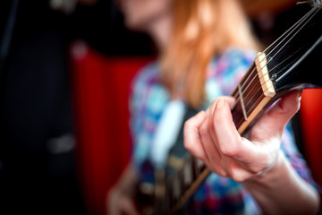 Female singer with electric guitar recording a song in studio