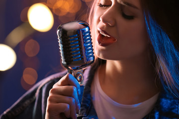 Beautiful female singer with microphone on stage, closeup