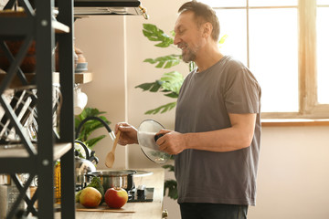 Handsome mature man cooking in kitchen