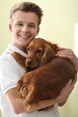 Teenage boy with cute dog on color background