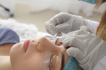 Fototapeta na wymiar Young woman undergoing procedure of eyelashes lamination in beauty salon