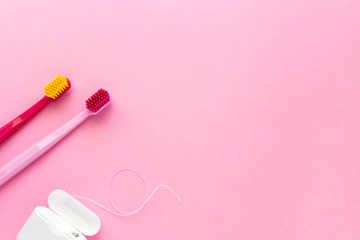 Dental hygiene - tooth brushes, dental floss flat lay, top view, copy space, pink background