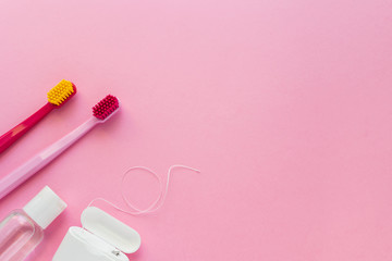 Dental hygiene - tooth brushes, dental floss, mouthwash flat lay, top view, copy space, pink background