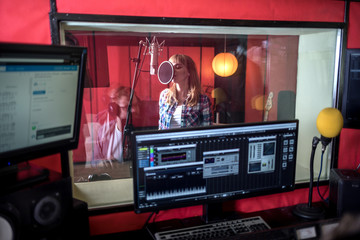 Female singer during vocal recording at music studio - Powered by Adobe
