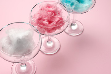 Glasses with tasty cotton candy on color background