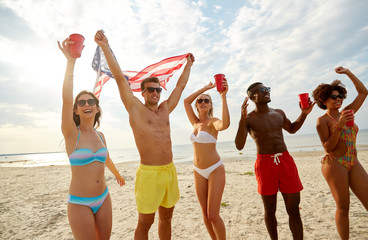 summer, holidays and people concept - group of happy friends with flag and non-alcoholic drinks celebrating american independence day and party on beach