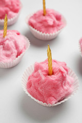 Tasty cotton candy with candles on grey background