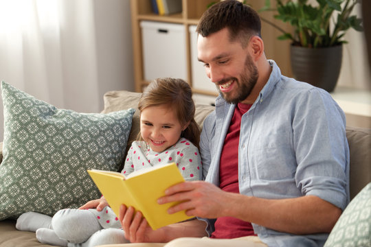 family, leisure and people concept - happy father and daughter reading book at home