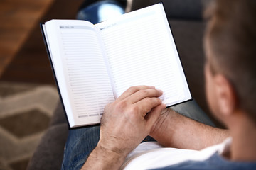 Handsome mature man with notebook at home