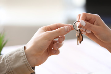 Real estate agent giving key from new house to young man in office