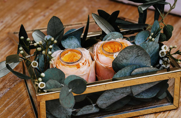 Two wedding rings in a golden box decorated with roses and leaves. Close up image.