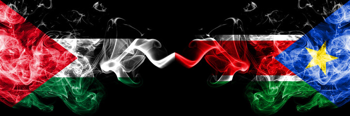 Palestine vs South Sudan smoky mystic flags placed side by side. Thick colored silky smokes flag of Palestinians and South Sudan