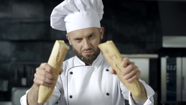 Male chef breaking french bread in slow motion. Closeup hands breaking bread.