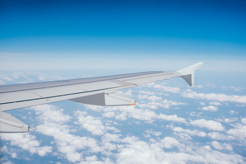 Wing of the airplane with the view of beautiful blue sky and clouds.