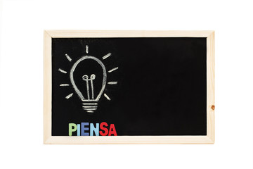Bombilla dibujada sobre pizarra negra con escritura piensa. Copy space