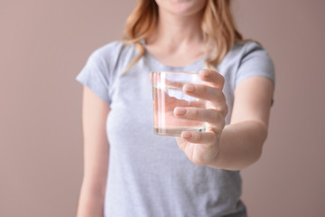 Woman with glass of fresh water on color background