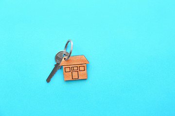 Key with trinket in shape of house on color background
