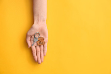 Female hand with key from house on color background